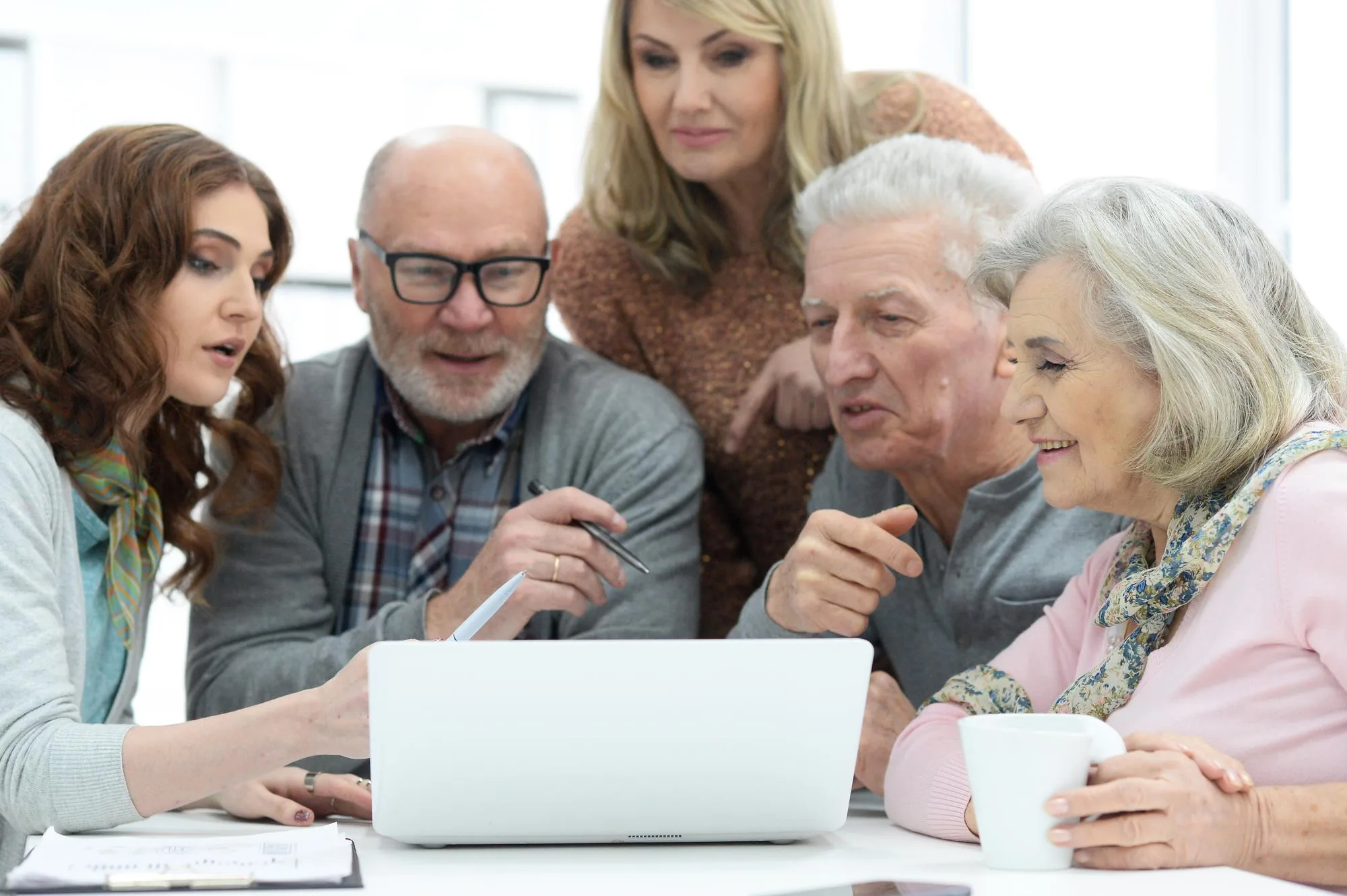Jüngere und ältere Menschen besprechen gemeinsam etwas an einem Laptop
