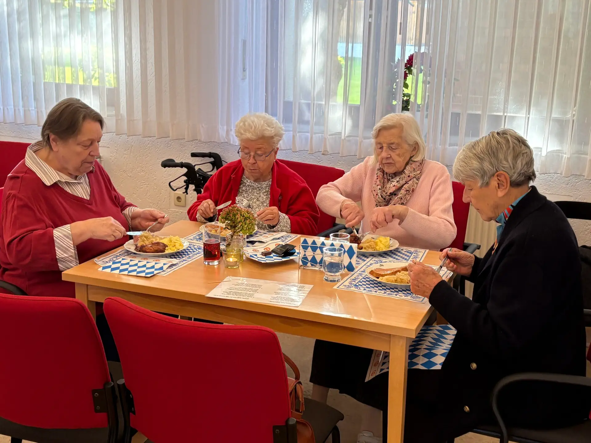 Vier Seniorinnen essen an einem Tisch mit blau-weißer Dekoration