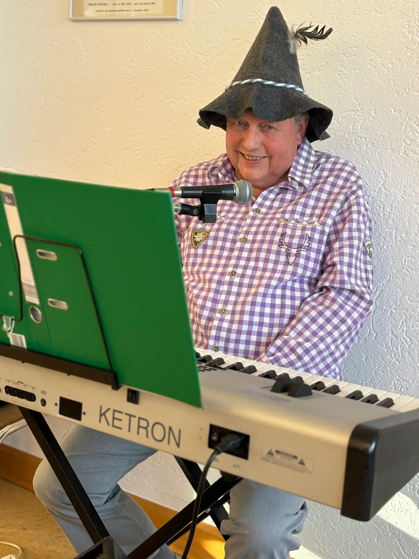 Mann mit Trachtenhut spielt Keyboard und singt ins Mikrofon