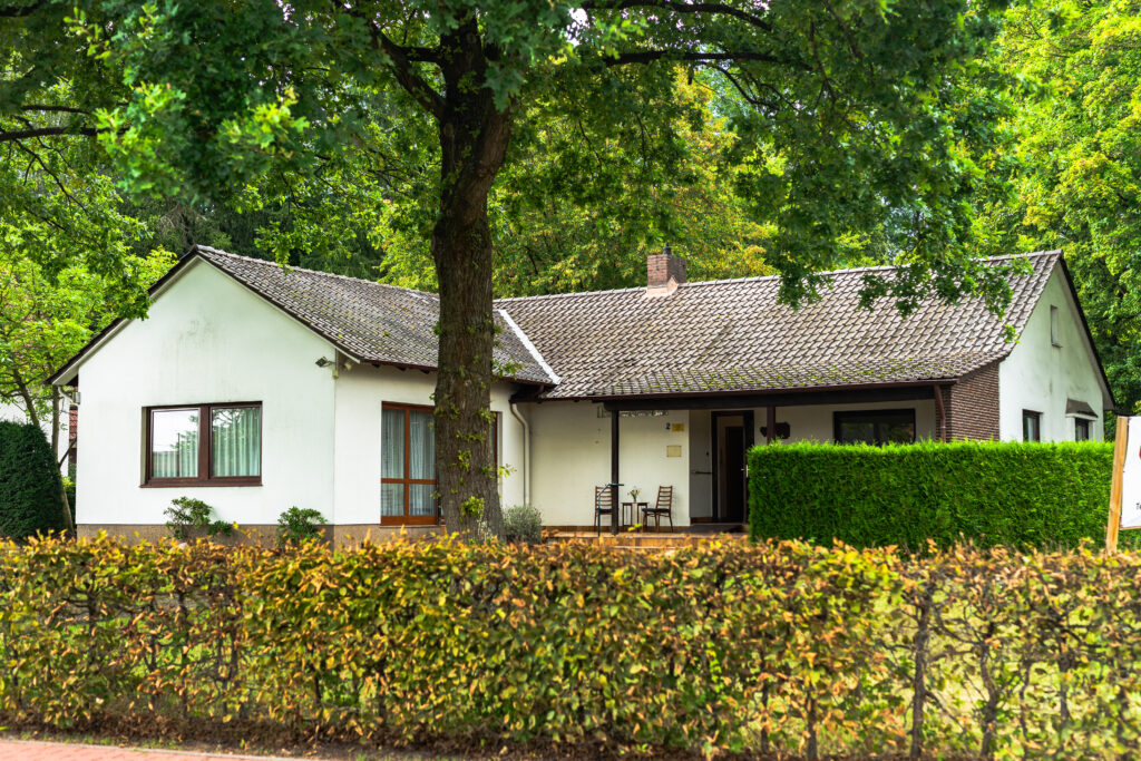 Weißes Gebäude des AWO Treffpunkts Obernbeck mit Hecke und Bäumen