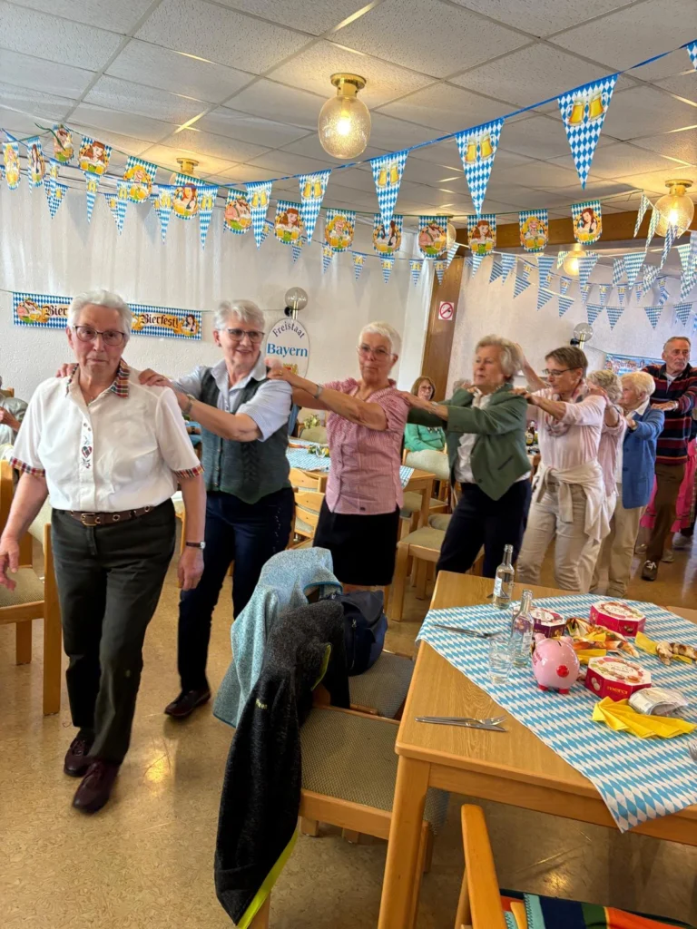 Gäste, teils in Trachtenbluse und Trachtenweste, ziehen in einer Polonaise durch den geschmückten Saal
