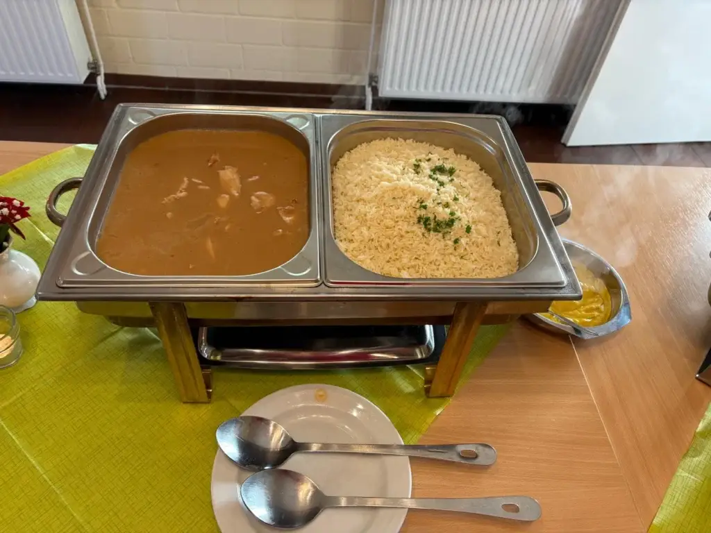 Warmhaltebehälter mit Züricher Geschnetzeltem und Butterreis auf einem Buffettisch