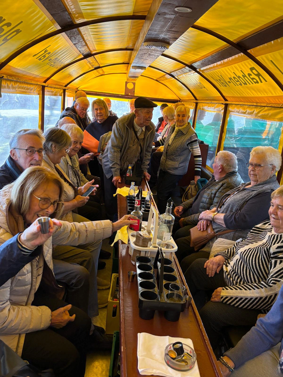 Gäste im Planwagen stoßen mit kleinen Bechern an, an der gelben Plane steht „Rahden-Varl“