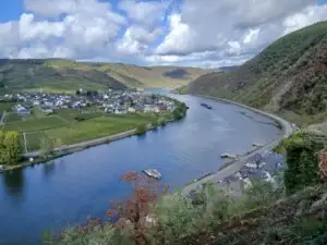 Blick von oben auf die Mosel mit einem Frachtschiff, links der Ort Ellenz-Poltersdorf zwischen Weinbergen, rechts unten die Dächer von Beilstein